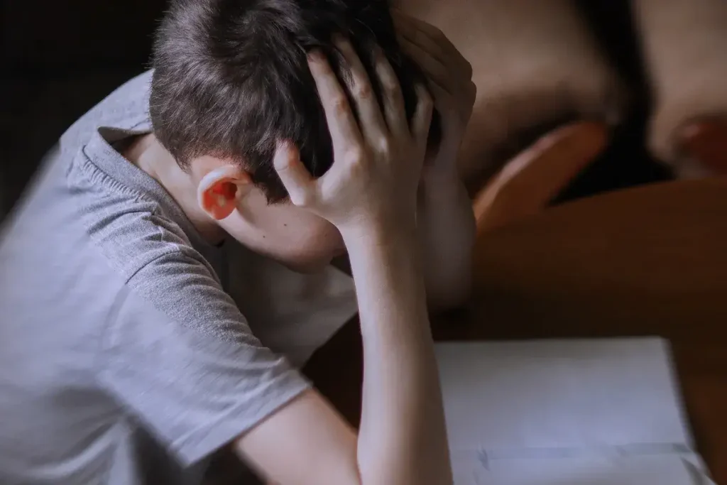 bambino su un banco di scuola in difficoltà davanti a carta e penna