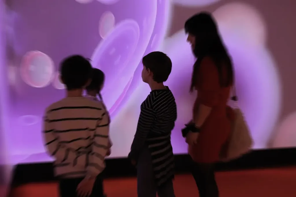 Bambini e insegnante in aula Miri davanti a contenuti immersivi proiettati, apprendimento attraverso immagini e gioco