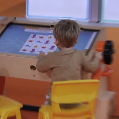 Bambino e insegnante al banco interattivo Pinguin durante un’attività digitale guidata